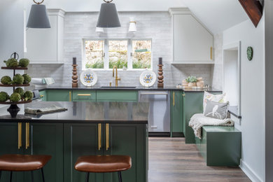 Inspiration for a transitional u-shaped vinyl floor, brown floor and vaulted ceiling eat-in kitchen remodel in Other with an undermount sink, flat-panel cabinets, green cabinets, white backsplash, ceramic backsplash, stainless steel appliances, an island, black countertops and quartz countertops