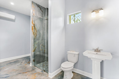 Walk-in shower - large contemporary multicolored tile and ceramic tile concrete floor, multicolored floor and single-sink walk-in shower idea in Miami with white cabinets, a two-piece toilet, blue walls, a pedestal sink, a hinged shower door and a freestanding vanity