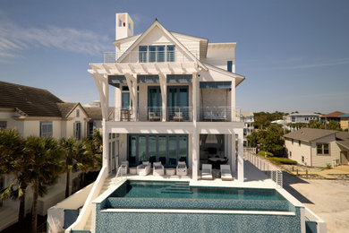 Beach style white three-story mixed siding and shingle exterior home photo in Miami with a metal roof and a gray roof