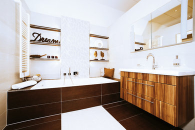 Klassisches Badezimmer mit flächenbündigen Schrankfronten, hellbraunen Holzschränken, Einbaubadewanne, weißen Fliesen, Keramikfliesen, Keramikboden, Einbauwaschbecken und braunem Boden in Sonstige