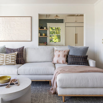Bright Living Room with Off-White Sectional, White Coffee Table, and Kitchen Vie
