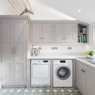 ケントの小さいトランジショナルスタイルのおしゃれな洗濯室 (シングルシンク、インセット扉のキャビネット、グレーのキャビネット、珪岩カウンター、白い壁、セラミックタイルの床、左右配置の洗濯機・乾燥機、マルチカラーの床) の写真