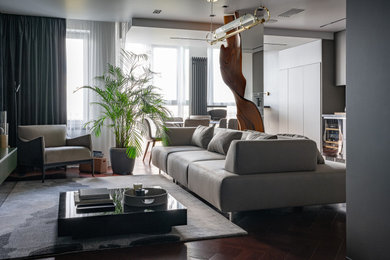 На фото: серо-белая, открытая, объединенная гостиная комната в современном стиле с белыми стенами, темным паркетным полом, красным полом и телевизором на стене