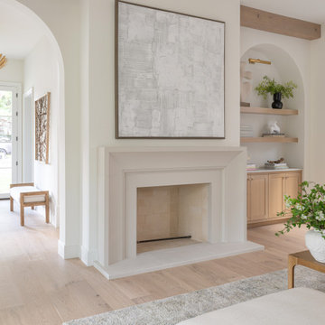 Hand-finished plaster fireplace flanked by arched built-ins and white