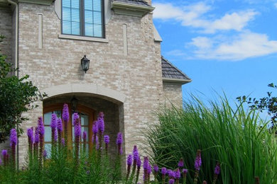 Inspiration for a large timeless gray two-story stone house exterior remodel in Chicago with a hip roof and a shingle roof