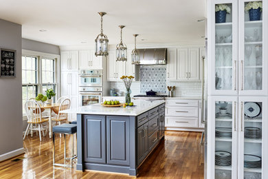 Kitchen - mid-sized transitional l-shaped medium tone wood floor and brown floor kitchen idea in DC Metro with a farmhouse sink, raised-panel cabinets, white cabinets, quartz countertops, white backsplash, subway tile backsplash, stainless steel appliances and white countertops