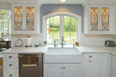 Inspiration for a mid-sized country u-shaped medium tone wood floor eat-in kitchen remodel in Philadelphia with a farmhouse sink, white cabinets, soapstone countertops, white backsplash, stainless steel appliances and an island