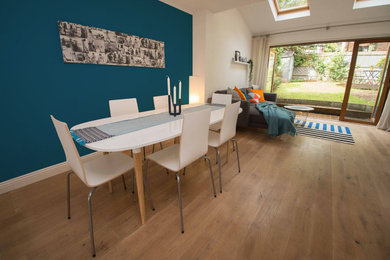 Inspiration for a medium sized modern open plan dining room in Hertfordshire with blue walls, medium hardwood flooring and a feature wall.