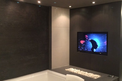 Imagen de cuarto de baño principal moderno de tamaño medio con armarios con paneles lisos, puertas de armario grises, jacuzzi, paredes grises, suelo de pizarra y encimera de granito
