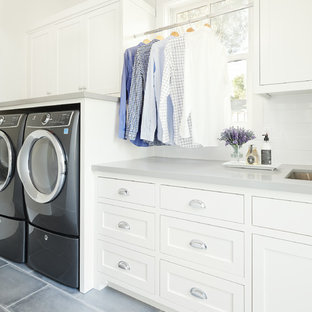 Выдающиеся фото от архитекторов и дизайнеров интерьера: отдельная, линейная прачечная в стиле кантри с врезной раковиной, фасадами в стиле шейкер, белыми фасадами, столешницей из кварцевого композита, белыми стенами, полом из керамогранита, параллельным расположением стиральной и сушильной машин, серым полом и серой столешницей