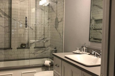 Inspiration for a small transitional white tile and porcelain tile porcelain tile and white floor tub/shower combo remodel in Dallas with flat-panel cabinets, white cabinets, an undermount tub, a two-piece toilet, gray walls, a drop-in sink, quartz countertops, a hinged shower door and gray countertops