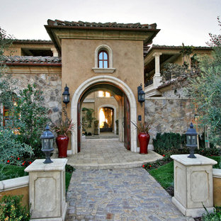 サンディエゴの巨大な両開きドア地中海スタイルのおしゃれな玄関ドア (茶色い壁、レンガの床、木目調のドア、グレーの床) の写真