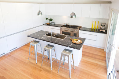 This is an example of a mid-sized industrial eat-in kitchen in Sydney with flat-panel cabinets, white cabinets, marble benchtops, white splashback, with island and subway tile splashback.