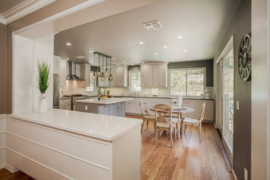 This is an example of a large transitional l-shaped eat-in kitchen in Los Angeles with white cabinets, stainless steel appliances, light hardwood floors, with island, subway tile splashback, an undermount sink, recessed-panel cabinets, quartz benchtops and white splashback.