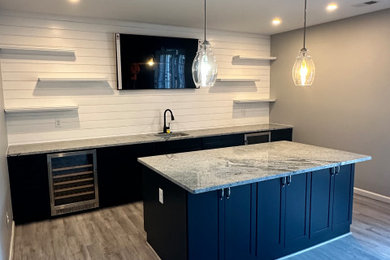 Example of a mid-sized mid-century modern galley laminate floor and gray floor wet bar design in DC Metro with an undermount sink, shaker cabinets, blue cabinets, granite countertops, white backsplash, shiplap backsplash and multicolored countertops