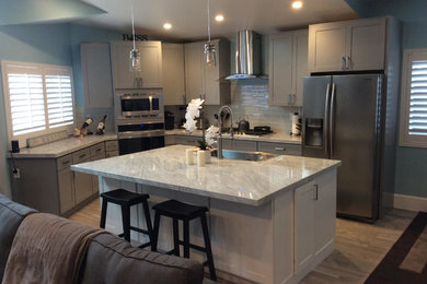 Inspiration for a coastal porcelain tile and brown floor kitchen remodel in Orange County with a single-bowl sink, shaker cabinets, gray cabinets, quartz countertops, gray backsplash, glass tile backsplash, stainless steel appliances, an island and gray countertops