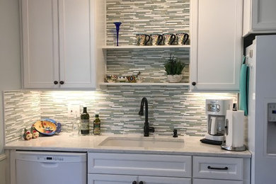 Inspiration for a mid-sized traditional l-shaped separate kitchen in Kansas City with an undermount sink, shaker cabinets, white cabinets, quartz benchtops, green splashback, mosaic tile splashback, white appliances, vinyl floors, no island and brown floor.