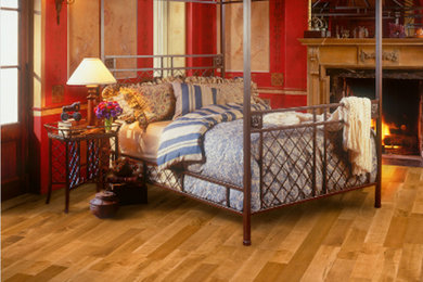 Example of a mid-sized trendy master light wood floor and beige floor bedroom design in Phoenix with red walls, a standard fireplace and a wood fireplace surround