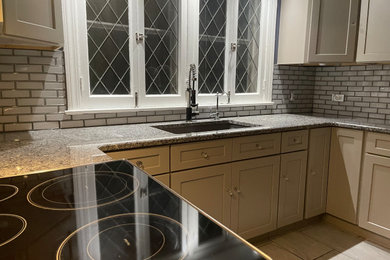 Eat-in kitchen - large contemporary u-shaped porcelain tile eat-in kitchen idea in New York with an undermount sink, shaker cabinets, gray cabinets, granite countertops, metallic backsplash, glass tile backsplash, stainless steel appliances and gray countertops
