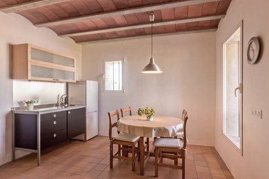 Photo of a mid-sized country eat-in kitchen in Other with terra-cotta floors.