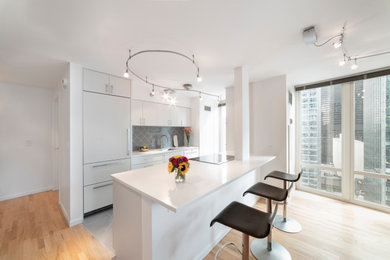 Inspiration for a small contemporary galley porcelain tile and gray floor kitchen remodel in Chicago with an undermount sink, flat-panel cabinets, white cabinets, quartz countertops, gray backsplash, porcelain backsplash, paneled appliances, a peninsula and white countertops