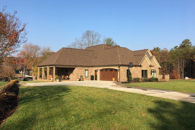 Example of a mid-sized transitional beige two-story brick exterior home design in Raleigh with a hip roof
