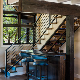 Idee per un piccolo bancone bar stile rurale con ante in stile shaker, ante in legno bruno, top in granito, paraspruzzi nero, paraspruzzi in granito, pavimento in legno massello medio, pavimento marrone e top nero