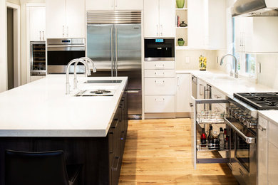 Large trendy light wood floor and brown floor eat-in kitchen photo in Denver with an undermount sink, flat-panel cabinets, white cabinets, white backsplash, stainless steel appliances and an island