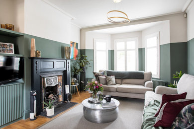 This is an example of a medium sized victorian living room feature wall in Belfast with green walls, medium hardwood flooring, a standard fireplace, a wooden fireplace surround and a built-in media unit.
