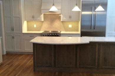 Design ideas for a large traditional single-wall separate kitchen in Boston with shaker cabinets, white cabinets, quartzite benchtops, beige splashback, subway tile splashback, stainless steel appliances, light hardwood floors, with island, brown floor and white benchtop.