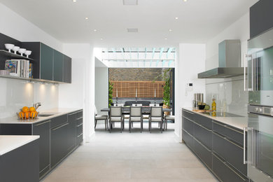 Photo of a large contemporary galley eat-in kitchen in London with flat-panel cabinets, grey cabinets and white splashback.