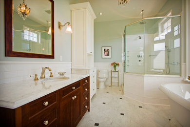 This is an example of a contemporary master bathroom in Vancouver with raised-panel cabinets, brown cabinets, a freestanding tub, a corner shower, a two-piece toilet, green walls, marble floors, a drop-in sink and marble benchtops.
