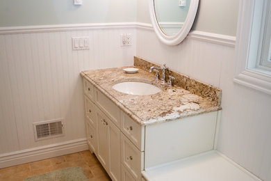 Example of a large classic brown tile and stone tile limestone floor alcove shower design in Grand Rapids with an undermount sink, shaker cabinets, white cabinets, granite countertops, a two-piece toilet and blue walls