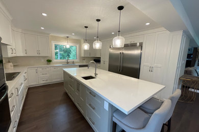 Kitchen - brown floor kitchen idea in Toronto with shaker cabinets, white cabinets, white backsplash, stainless steel appliances, an island and white countertops