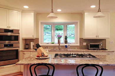 Eat-in kitchen - mid-sized transitional l-shaped medium tone wood floor and brown floor eat-in kitchen idea in New York with an undermount sink, shaker cabinets, white cabinets, granite countertops, gray backsplash, glass tile backsplash, stainless steel appliances, an island and multicolored countertops