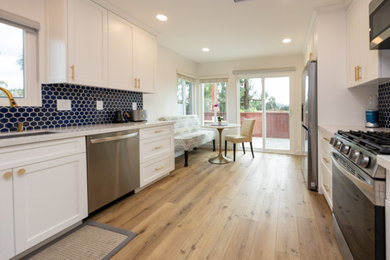Inspiration for a large contemporary galley linoleum floor and brown floor eat-in kitchen remodel in San Diego with an undermount sink, shaker cabinets, white cabinets, quartz countertops, blue backsplash, cement tile backsplash, stainless steel appliances and white countertops
