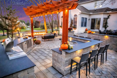 Modern back patio in Philadelphia with a fire feature, concrete paving and a pergola.