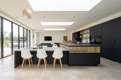 Design ideas for a large modern kitchen in Other with a submerged sink, flat-panel cabinets, black cabinets, composite countertops, white splashback, ceramic splashback, black appliances, porcelain flooring, an island, grey floors, black worktops and feature lighting.