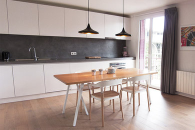 This is an example of a mid-sized modern single-wall eat-in kitchen in Lyon with beaded inset cabinets, grey cabinets, grey splashback, light hardwood floors, no island and grey benchtop.