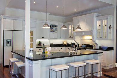 Large traditional l-shaped eat-in kitchen in Perth with white cabinets, white splashback, medium hardwood floors, with island, raised-panel cabinets and stainless steel appliances.