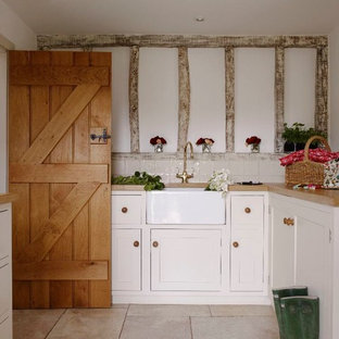 Diseño de lavadero de galera, romántico, de tamaño medio, con armarios estilo shaker, fregadero sobremueble, puertas de armario blancas, encimera de madera y paredes blancas
