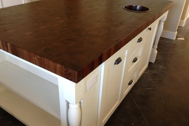 Example of a large trendy galley concrete floor and brown floor eat-in kitchen design in Austin with an undermount sink, recessed-panel cabinets, white cabinets, wood countertops and an island