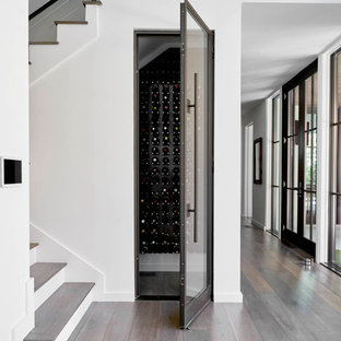 Foto på en liten funkis vinkällare, med mörkt trägolv, vinhyllor och brunt golv