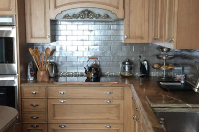 Example of a mid-sized eclectic u-shaped marble floor enclosed kitchen design in Chicago with a farmhouse sink, raised-panel cabinets, light wood cabinets, quartzite countertops, metallic backsplash, subway tile backsplash, paneled appliances and an island