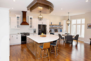 Example of a mid-sized transitional l-shaped medium tone wood floor, brown floor and wood ceiling eat-in kitchen design in Minneapolis with a double-bowl sink, shaker cabinets, white cabinets, quartzite countertops, white backsplash, ceramic backsplash, black appliances, an island and white countertops