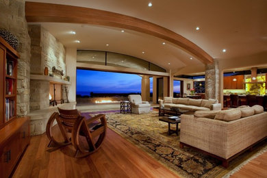 Example of a classic open concept medium tone wood floor living room design in Orange County with beige walls, a standard fireplace and a stone fireplace