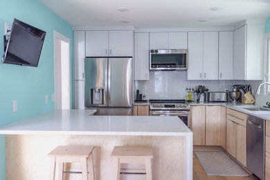 Example of a danish light wood floor kitchen design in Minneapolis with flat-panel cabinets, quartzite countertops and stainless steel appliances
