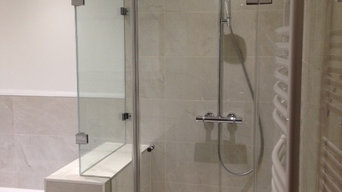 Bathroom installation with bespoke glass shower surround on shelf wall.