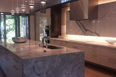 Modern kitchen in Toronto with an undermount sink, white cabinets, quartzite benchtops, white splashback, stone slab splashback, stainless steel appliances and with island.