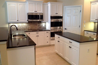 Example of a mid-sized classic u-shaped ceramic tile kitchen design in Miami with an island, an undermount sink, raised-panel cabinets, white cabinets, quartzite countertops, brown backsplash, stone tile backsplash and stainless steel appliances